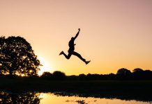 empreendedor saltando sobre lago ao por do sol
