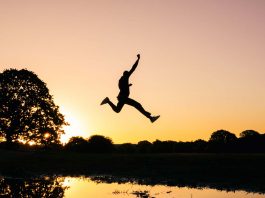 empreendedor saltando sobre lago ao por do sol